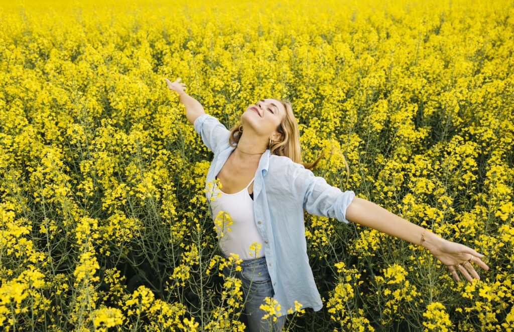 Mujer con los brazos abiertos en un campo de flores